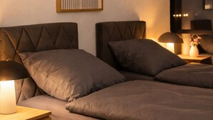 Una cama doble con cabecera, dos mesitas de noche con lámparas, y una obra de arte abstracto colgada en la pared.