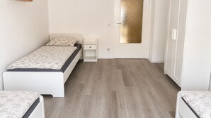 A bedroom with a bed, bedside table, wardrobe, and a door with a textured glass panel. - Well-kept apartment for fitters & project teams with 2 bedrooms in Mannheim (Mannheim)