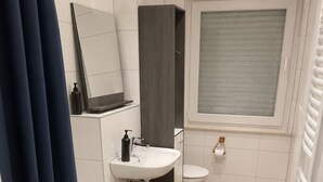 A modern bathroom with a bathtub, sink, and toilet. - Well-kept apartment for fitters & project teams with 2 bedrooms in Mannheim (Mannheim)