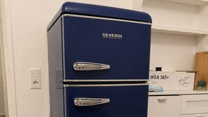 A blue SEVERIN refrigerator in a kitchen with white cabinets and a wooden floor. - Well-kept apartment for fitters & project teams with 2 bedrooms in Mannheim (Mannheim)