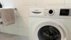 Etukuormattava pesukone, jossa on ohjauspaneeli, digitaalinen näyttö ja pyyhe kuivumassa pyyhetelineessä.