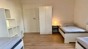 Makuuhuoneessa on kaksi sänkyä, vaatekaappi ja yöpöytä, jossa on lamppu.