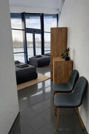 A modern interior with a large window, a wooden sideboard, a dark sofa, and a chair.