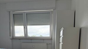 Ett sovrum med en säng, ett element, ett fönster med persienner och en garderob.