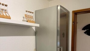 A compact kitchen with a built-in refrigerator, a white countertop, and a small stool. - Worker's apartment Rheinhausen (ground floor) (Oberhausen-Rheinhausen)