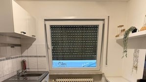 A compact kitchen with a window, radiator, and a sink. - Worker's apartment Rheinhausen (ground floor) (Oberhausen-Rheinhausen)