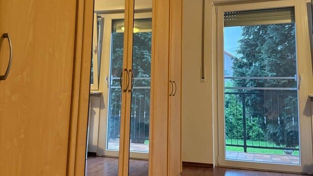 A room with a sliding door, a large window, and a view of a balcony. - Worker's apartment Rheinhausen (ground floor) (Oberhausen-Rheinhausen)
