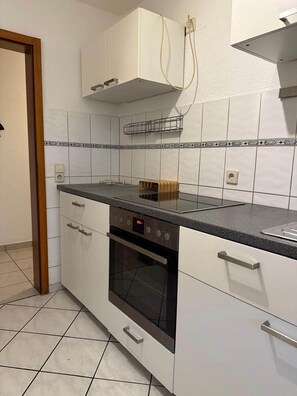 A kitchen with white cabinets, a black countertop, and a built-in oven.