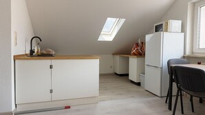 A compact kitchen with a wooden countertop, a refrigerator, a microwave, and a small dining area with a chair. - Fitters' apartment Oberhausen-Rheinhausen, Lönsweg 3, DG (Oberhausen-Rheinhausen)