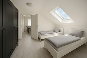 Un dormitorio con tragaluces, dos camas, un escritorio y una silla.