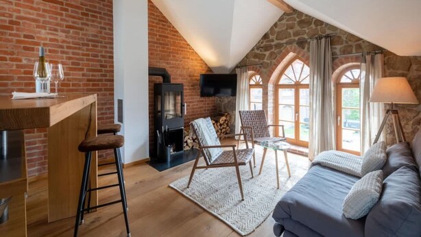 Ein Loft-Zimmer mit Backsteinwand, Kamin, Fernseher, einer Couch und einem Essbereich mit Tisch und Stühlen.
