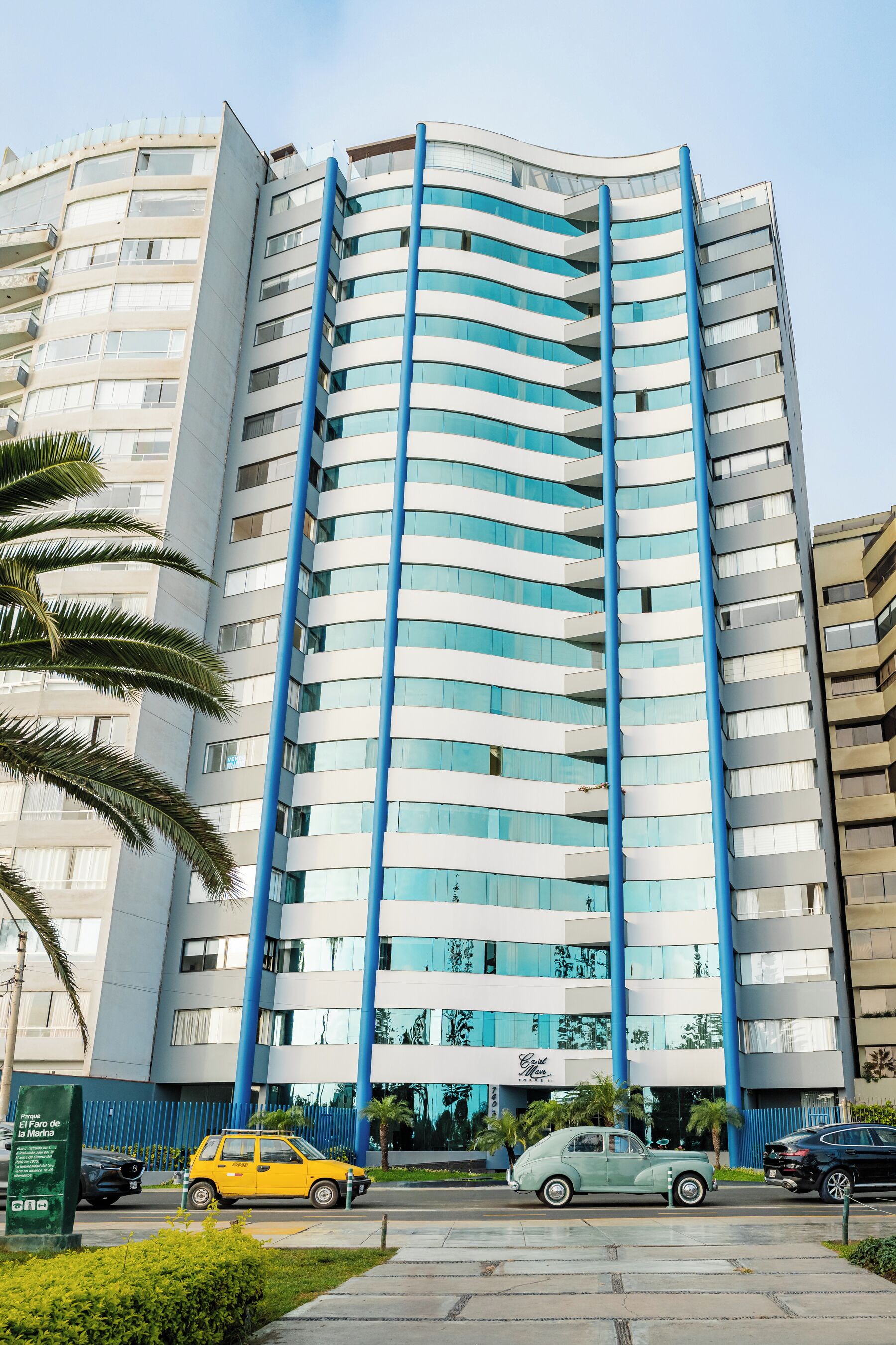Un immeuble à plusieurs étages doté d’une façade incurvée, de grandes fenêtres et d’éléments verticaux bleus.