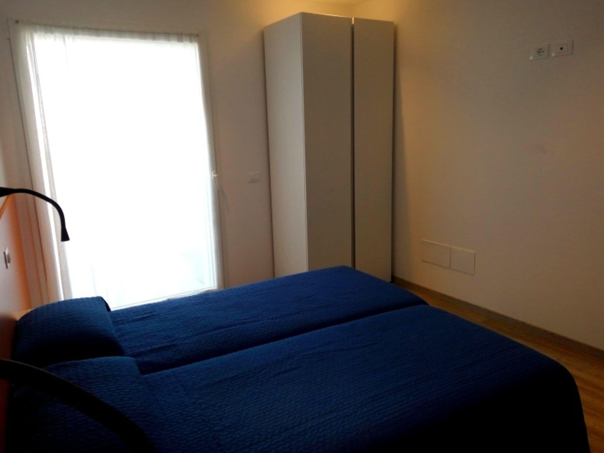 A bedroom with a bed, a wardrobe, and a window with curtains.