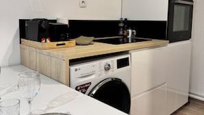 A compact kitchen with a washing machine, a coffee maker, and a microwave.