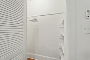 A white bathroom with a shower, a towel rack, and a wall-mounted control panel.