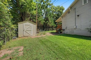 A house with a fenced yard, a shed, and a covered porch.
