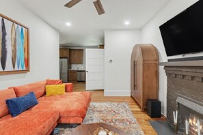 Ein Wohnzimmer mit einer Couch, einem Kamin und einem Fernseher.