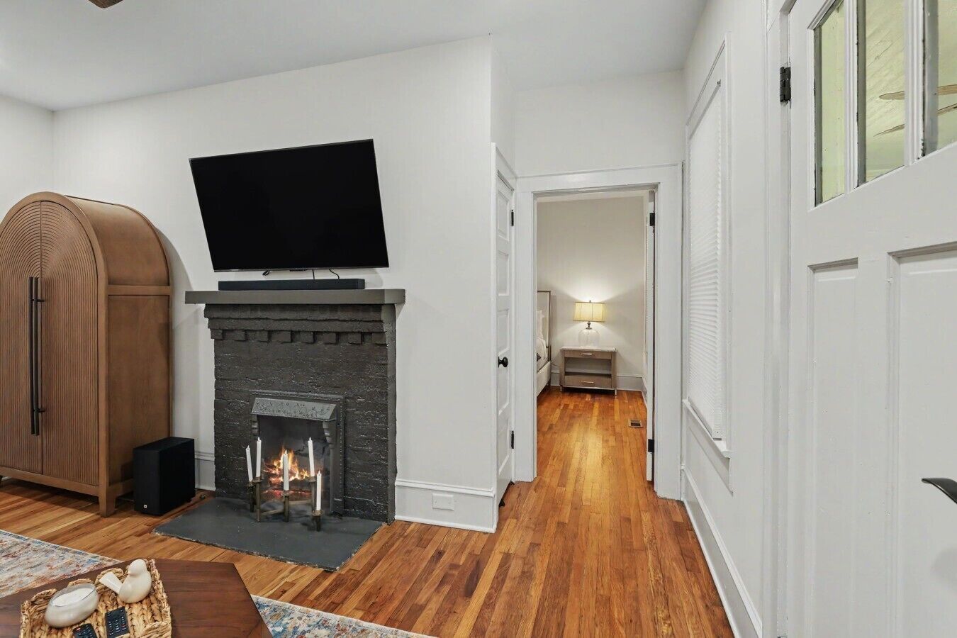 A living room with a fireplace, a television mounted above it, and a wooden cabinet.