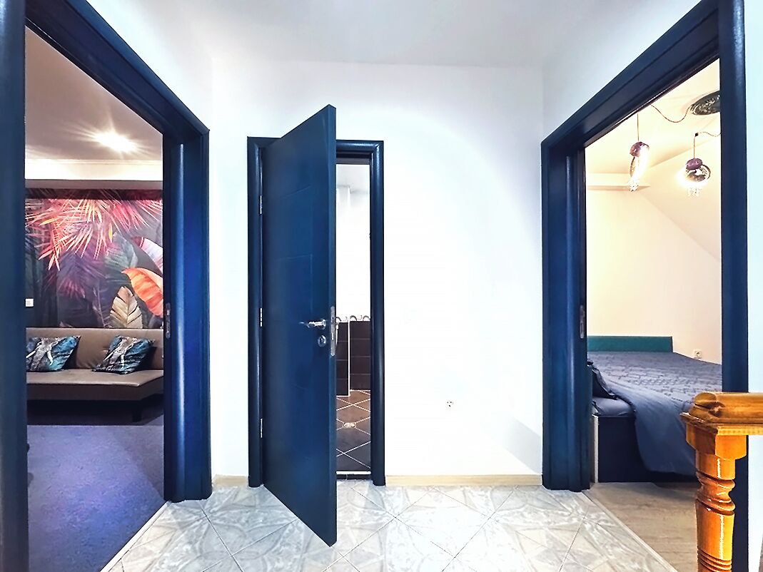 A room with a bed, a sofa, and a door leading to another room.