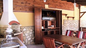 A rustic outdoor dining area with a stone wall, wooden furniture, and a brick oven. - BLUE PEARL 2-BEDROOM LUXURY MAISONETTE IN PANORAMIC ROOF COMPLEX (Balchik)