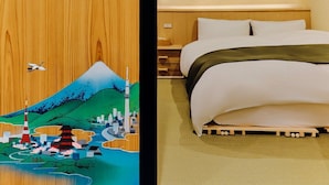 Een hotelkamer met een bed, een houten hoofdeinde en een wand met bloessemdesign.