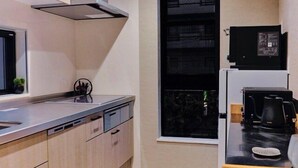 Een moderne keuken met een inbouwoven, een koffieapparaat en een raam met uitzicht op een gebouw.