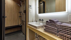 Een badkamer met een douchecabine van hout, een wastafel met spiegel en een handdoekrek.