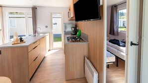 A compact kitchen with a flat-screen TV, a small stove, and a sink. - Premium Caravan in Erezee With Terrace (Erezee)