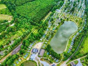 An aerial view of a campground with RVs, a large lake, and surrounding greenery. - Premium Caravan in Erezee With Terrace (Erezee)