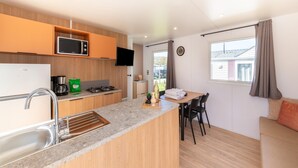 A compact kitchenette with a microwave, coffee maker, and sink. There is a dining area with a table and chairs, and a sofa. - Premium Caravan in Erezee With Terrace (Erezee)