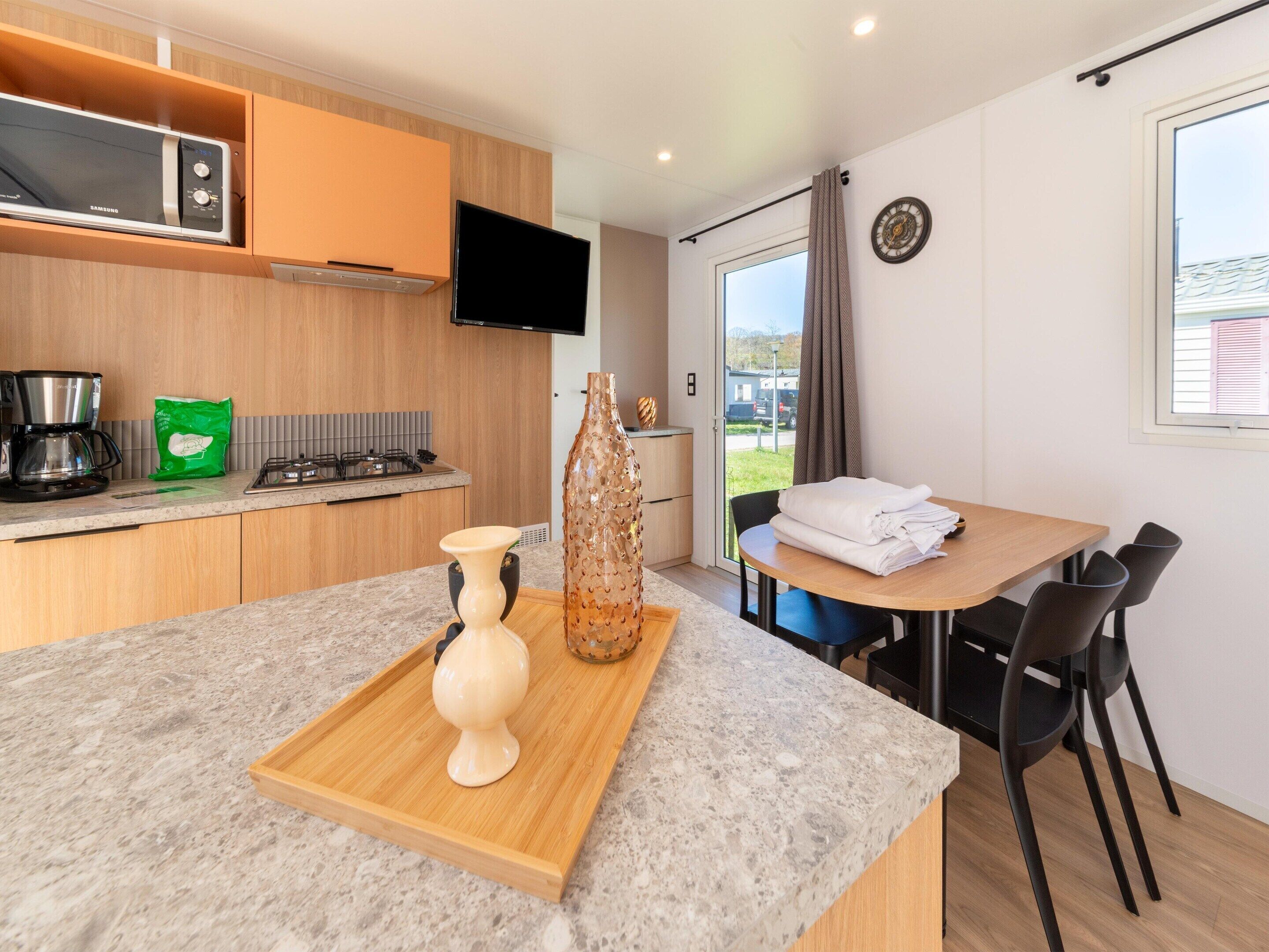 A modern kitchen with a microwave, coffee maker, and a green bag on the counter.