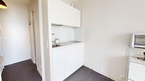 Een compact en net keukenhoekje met een spoelbak, aanrecht en een magnetron.