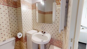 A bathroom with patterned wallpaper, a white sink, a toilet, and a mirror. - Belle Isle - Breathtaking Ocean Views (La Baule-Escoublac)
