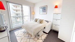 A modern bedroom with a bed, a desk, a chair, a wardrobe, and a balcony with a view. - Belle Isle - Breathtaking Ocean Views (La Baule-Escoublac)