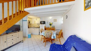 Ett kompakt bostadsutrymme med ett kök, en matplats och en soffa.