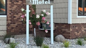 A motel sign with a brick facade and a flower arrangement. - Mushroom Cap Motel (Mesick)