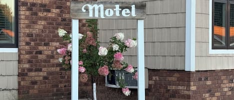 A motel sign with a brick facade and a flower arrangement.