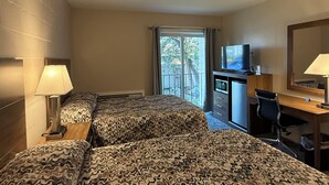A hotel room with two beds, a desk, a chair, a TV, and a window with a view. - Mushroom Cap Motel (Mesick)