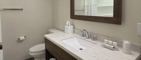 A bathroom with a white sink, a mirror, a toilet, and a towel rack.
