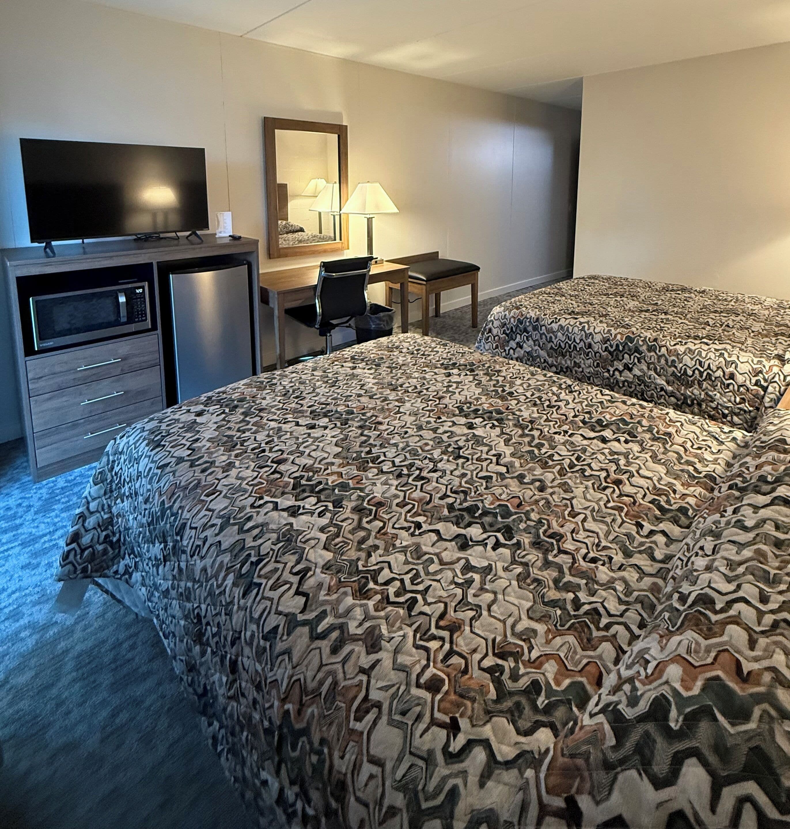 Une chambre d’hôtel équipée d’un lit, d’un bureau, d’une chaise, d’une télévision et d’un four à micro-ondes.