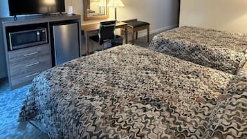 Une chambre d’hôtel équipée d’un lit, d’un bureau, d’une chaise, d’une télévision et d’un four à micro-ondes.