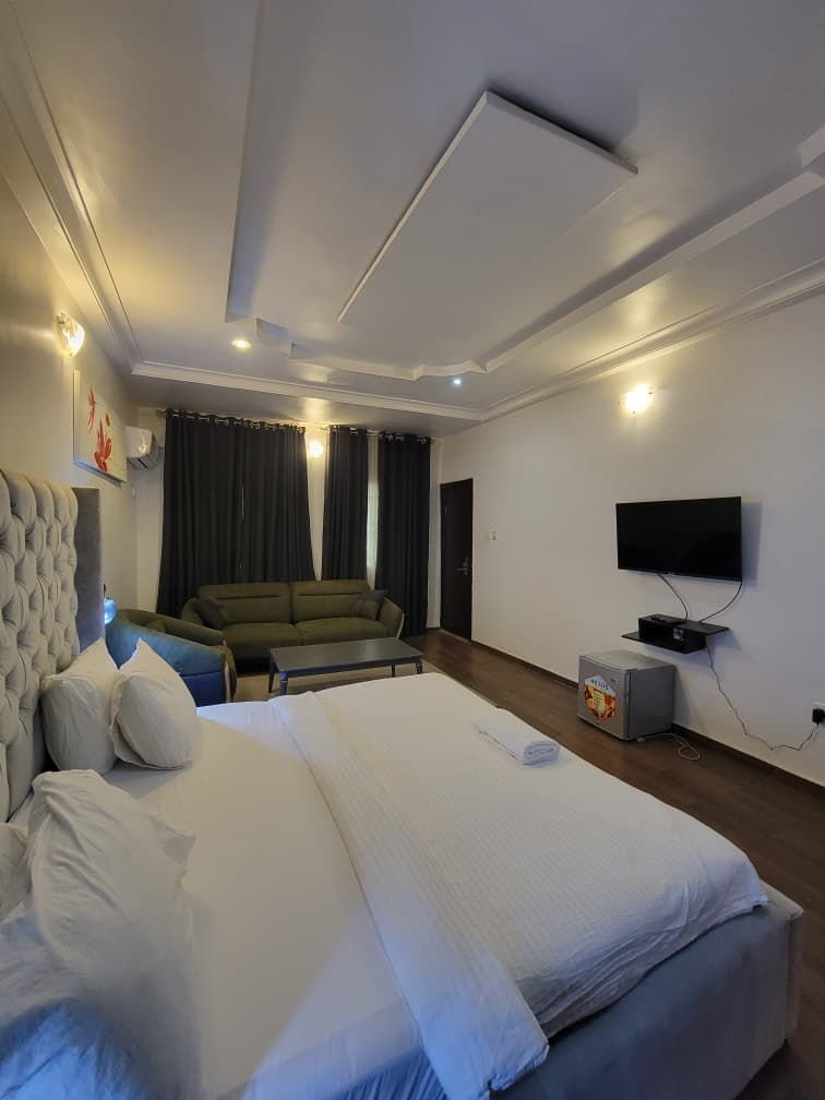 A hotel room with a large bed, a sofa, a television, and a small table.