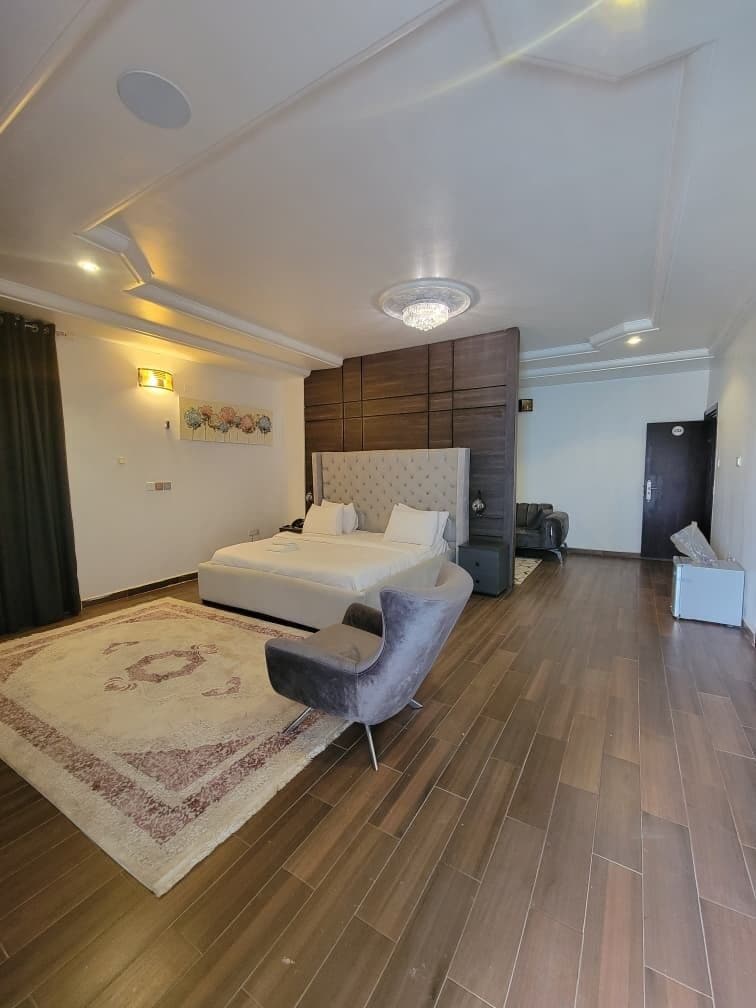 A modern bedroom with a large bed, a vanity, and a seating area.