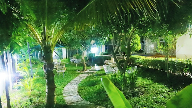 A garden area with a pathway, chairs, and a small fountain. - Palladium Gardens Residence (Abuja)