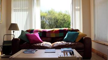 A living room with a brown leather sofa, a colorful blanket, and a wooden coffee table.