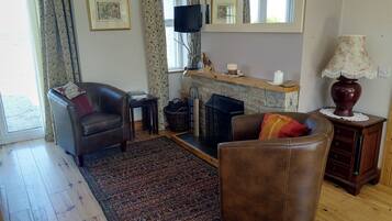 A living room with a fireplace, leather chairs, a rug, and a television.