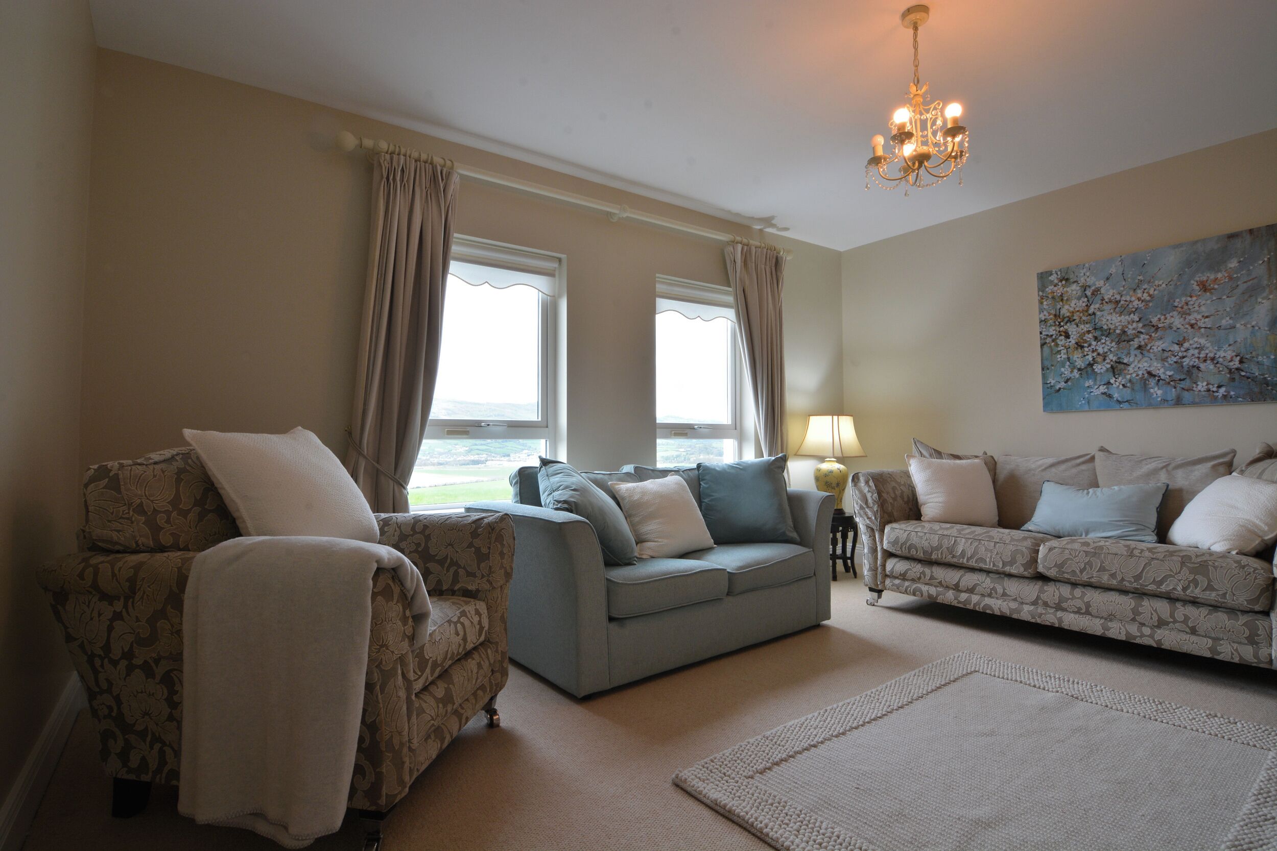 A living room with two sofas, a coffee table, a chandelier, and a painting on the wall.