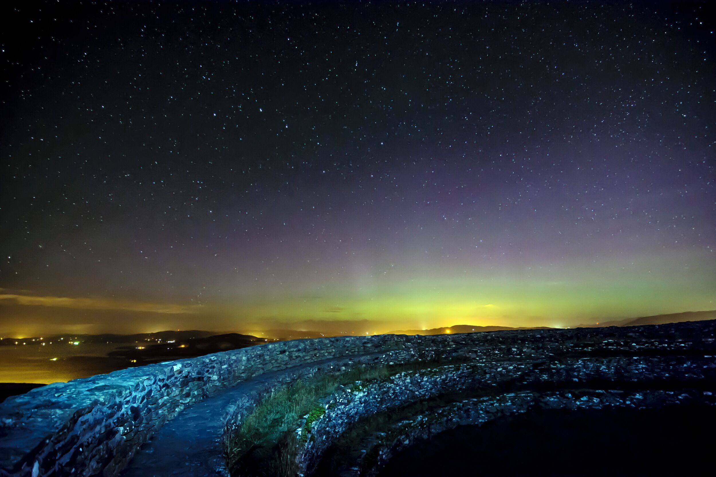Cielo estrellado sobre un paisaje rocoso con una carretera visible.