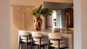 Cozinha moderna com bancada de mármore, um vaso de madeira com uma planta e um painel de parede em macramé.