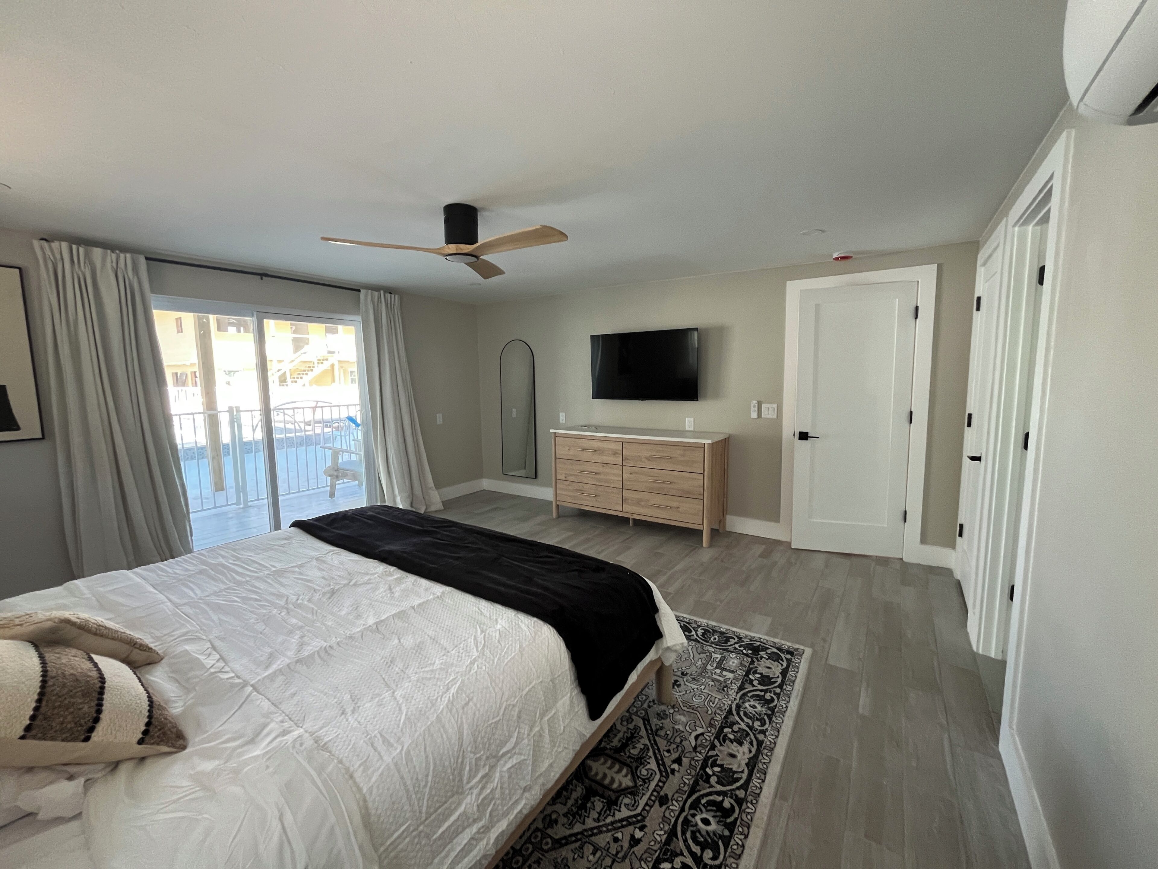 Ein Schlafzimmer mit Bett, Schminktisch, Fernseher und Deckenventilator.